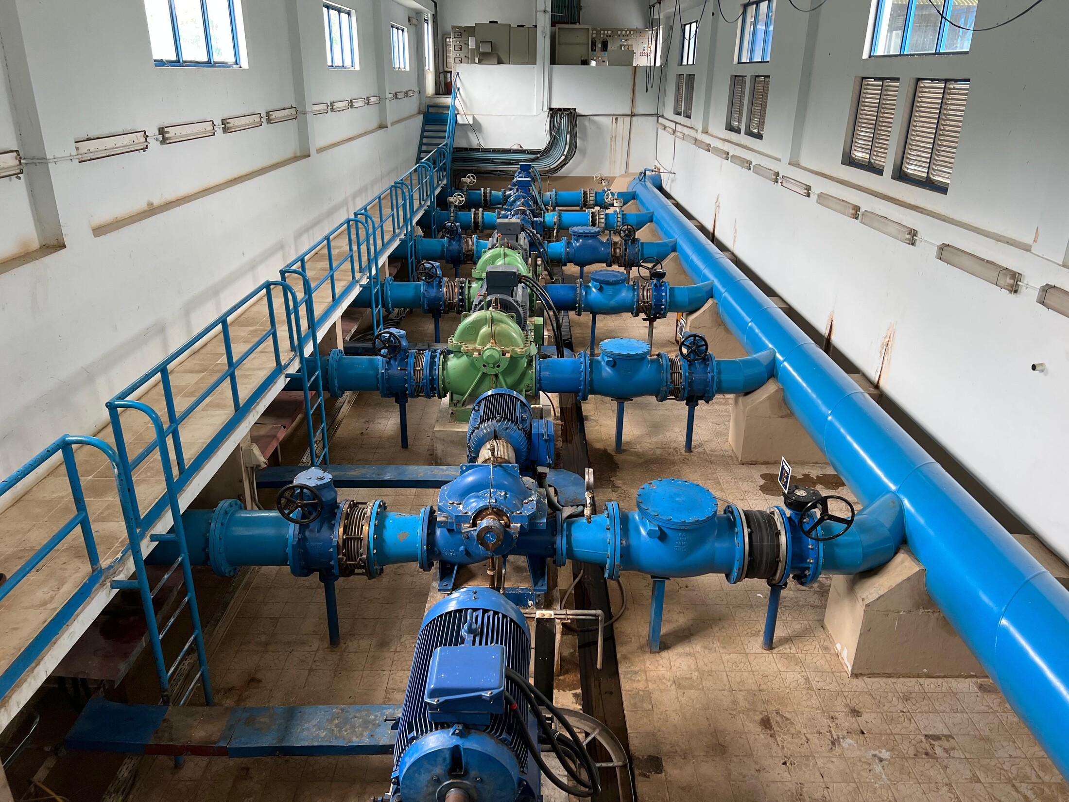 Municipal water pump gallery with large pumps, valves, and blue distribution piping